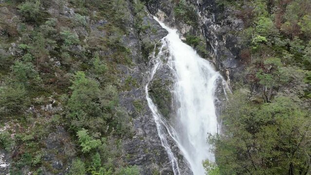 Push in shot Waterfall cascading though trees Lake Bohinj Slovenia drone aerial view