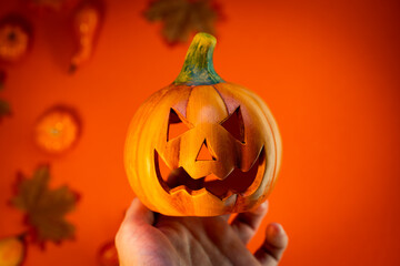 Ceramic Halloween Pumpkin held hand in front of an autumn themed orange background