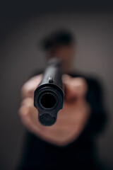 Man aiming and shooting with a gun. Focus on the pistol.