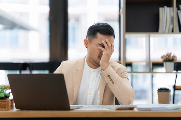 Obraz premium Stressed Asian businessman worry with many document on desk at office