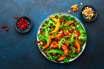 Healthy vegan eating, autumn pumpkin salad with baked honey pumpkin slices, lettuce, arugula,...