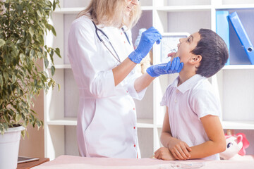 Fototapeta premium child at a pediatrician's appointment, the doctor checks the boy's throat