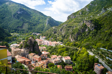 Fototapeta premium a small village surrounded by the Orsomarso Mountains. Green, forest-covered hills and rocks. Old, historic houses covered with red tiled roofs