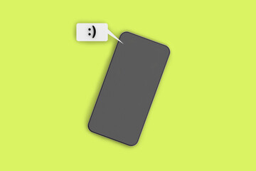 text message containing a character emoticon. Mobile phone on a light green background.View of the gadget from above. Communication between people. Smartphone. Horizontal image. 3d image. 3d rendering