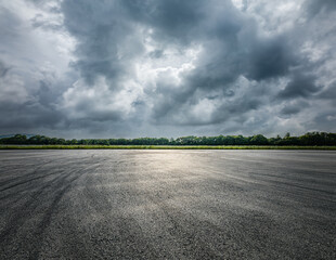 Empty asphalt road and green forest with sky clouds background