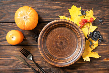Naklejka na ściany i meble Top view of blank halloween plate with pumpkins on a rustic table. Halloween table setting with cutlery. Festive concept.