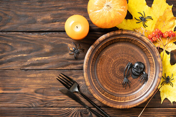 Top view of blank halloween plate with pumpkins on a rustic table. Halloween table setting with cutlery. Festive concept. Copy space.
