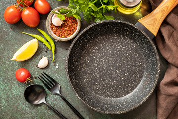 Food cooking background with Frying pan. Empty skillet, vegetables, spices and herbs on dark table background. View from above.