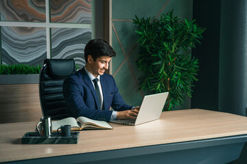 Businessman working with laptop in modern office. General manager,ceo. Young handsome confident man in suit sitting at table. Executive business leader. Entrepreneur career.Accountant bank workplace