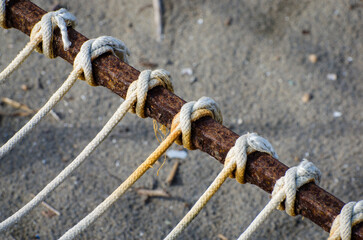 Dettaglio di alcune corde bianche legate in sequenza ad una sbarra di metallo arrugginito sulla spiaggia di Pellestrina