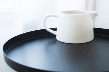 Obraz na płótnie Canvas White measuring cup for fresh milk, steamed milk and poured into coffee, placed on a black table.