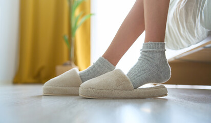 Cropped photo of unrecognizable child in socks with pulls socks, sitting on bed at home. morning....