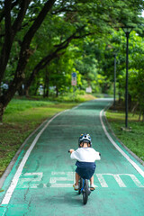 Little kindergarten boy ride a bike in public park