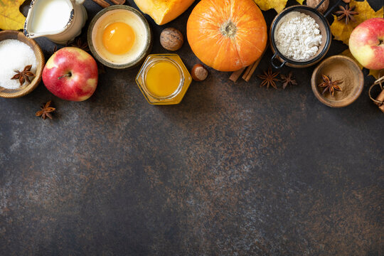 Autumn baking food background with pumpkins, apples, honey, nuts and seasonal spices on a stone table. Pumpkin or apple pie for Thanksgiving and autumn holidays. View from above. Copy space.