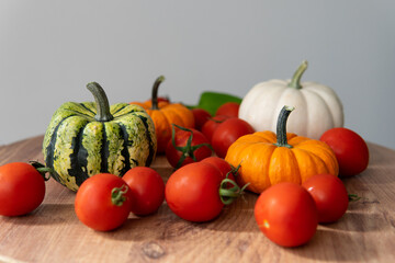 colorful pumpkins with tomatoes on a wooden table with a blurred background. autumn harvest atmosphere.