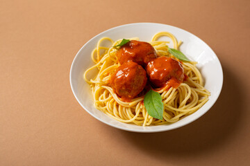 Tasty spaghetti with meat balls tomato sauce in white bowl  on brown surface italian food