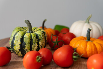 colorful pumpkins with tomatoes on a wooden table with a blurred background. autumn harvest atmosphere.
