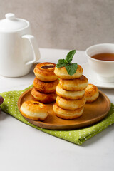 Cottage cheese pancakes on wooden plate, teapot and cup for breakfast food
