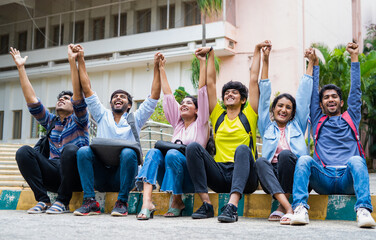 Fototapeta premium Excited group of students shouting by holding eachother hands after exams at on college campus - concept of friendship, bonding, happiness