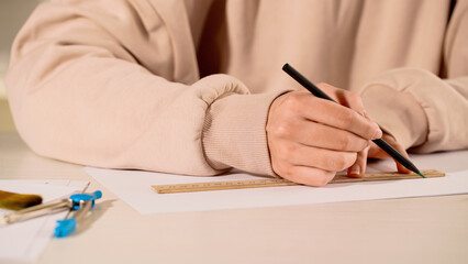 Cropped view of woman drawing with ruler and pencil at home.