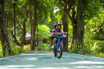 Little kindergarten boy ride a bike in public park