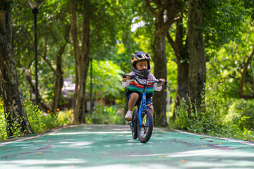 Naklejka premium Little kindergarten boy ride a bike in public park