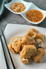 Fried tofu served in a white plate with tamarind sauce and mashed beans, fried tofu is a popular dish among Chinese and Asians.