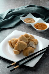 Fried tofu served in a white plate with tamarind sauce and mashed beans, fried tofu is a popular dish among Chinese and Asians.