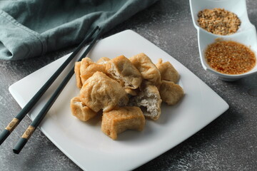 Fried tofu served in a white plate with tamarind sauce and mashed beans, fried tofu is a popular dish among Chinese and Asians.