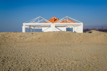 Uno stabilimento balneare con il tetto arancione, chiuso per la stagione invernale, sulla spiaggia di Punta Sabbioni a Venezia - obrazy, fototapety, plakaty