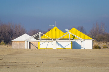 Uno stabilimento balneare con il tetto giallo, chiuso per la stagione invernale, sulla spiaggia di Punta Sabbioni a Venezia - obrazy, fototapety, plakaty