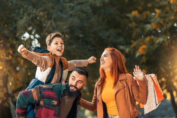 Young happy parents having fun with their boy while in the park during autumn day.