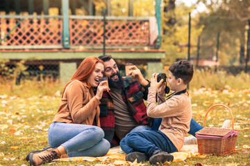 Young happy parents having fun with their boy in the park during autumn day