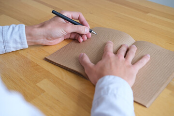 Close up of a person writing on vintage paper of kraft notebook