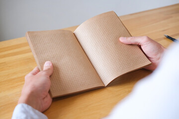 Hands holding a open notebook on the table