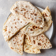 Delicious gourmet flat bread kutabs with herbs and cheese on a plate. Top view.