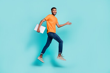 Fototapeta na wymiar Full body profile portrait of carefree cheerful guy running jump hold netbook isolated on cyan color background