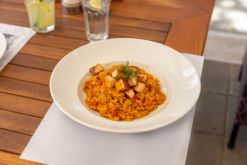 Risotto served in white plate on a restaurant table, top view