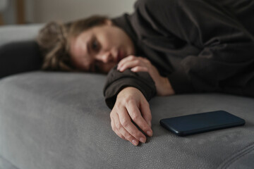 Caucasian woman with mental problem lying down with mobile phone on couch
