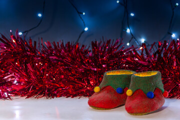 A pair of magical elf shoes full of Christmas light with a backdrop red tinsel and fairy lights