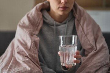 Close up of woman holding glass with pill dissolving in water