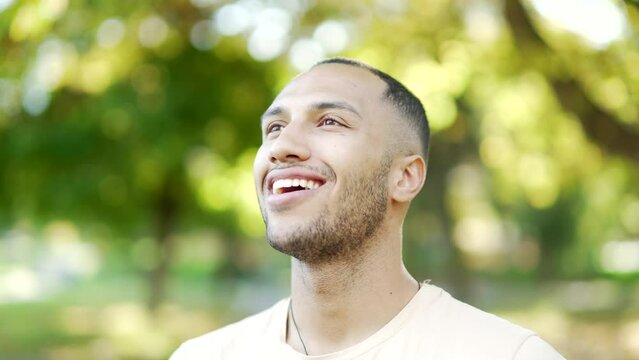 Close up portrait young happy handsome man standing in nature between forest trees relaxes, breathes fresh air closing his eyes Male enjoys a life of peace calm, quiet in the park. Outdoors. Happiness