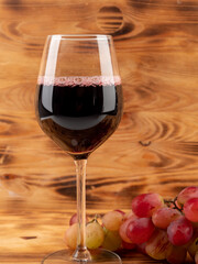 Glass of wine and grapes on a wooden background.