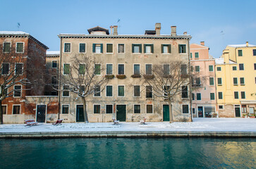 Fototapeta na wymiar Un canale di Venezia con le barche ve il marciapiede coperto dalla neve