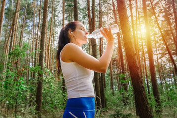 Young woman drinking water after jogging at summer,spring park,forest.