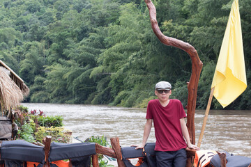 The man relaxed man in a crimson t-shirt enjoying nature breathing fresh air meditating on the river on a vacation day.
