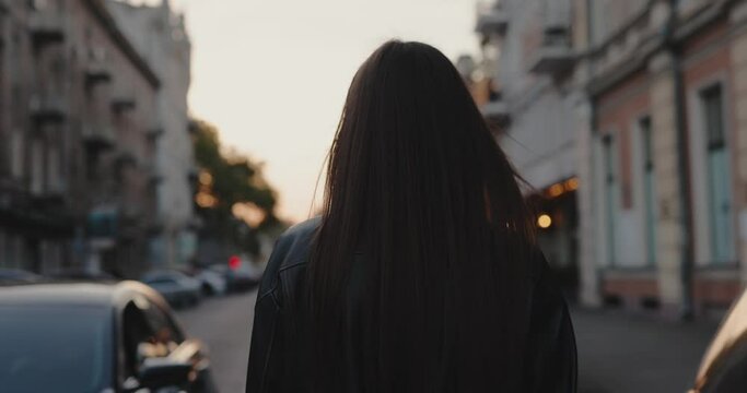 Charming woman walking at the city street turning face, slow motion, back view