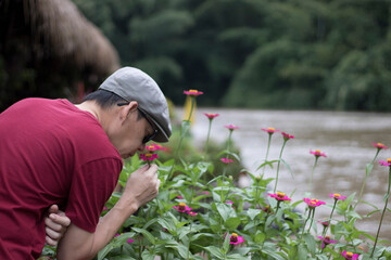 A Man smelling flower with closed eyes. on the river raft, focus blurred.  Slow living concept, vacation lifestyle.