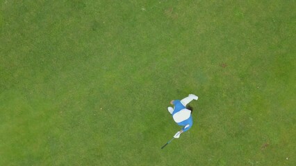 OVERHEAD AERIAL Drone shot of Caucasian female playing golf, striking a ball during the course