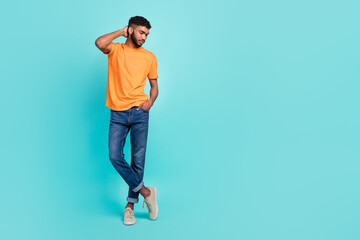 Fototapeta na wymiar Full length photo of serious confident guy wear orange t-shirt arm head looking empty space isolated teal color background
